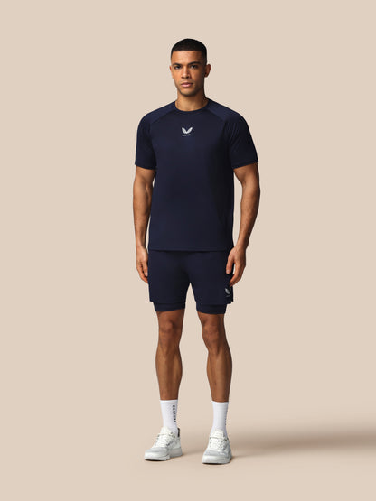 Man wearing a navy athletic outfit with a logo on a beige background