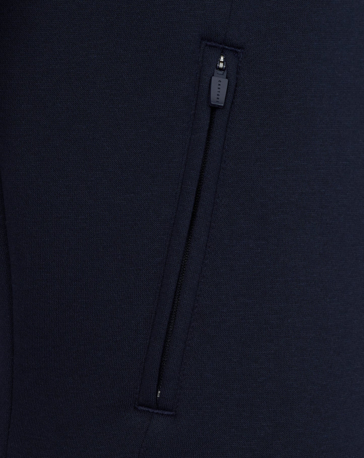 Close-up of a navy blue garment with a zipper on a matching background