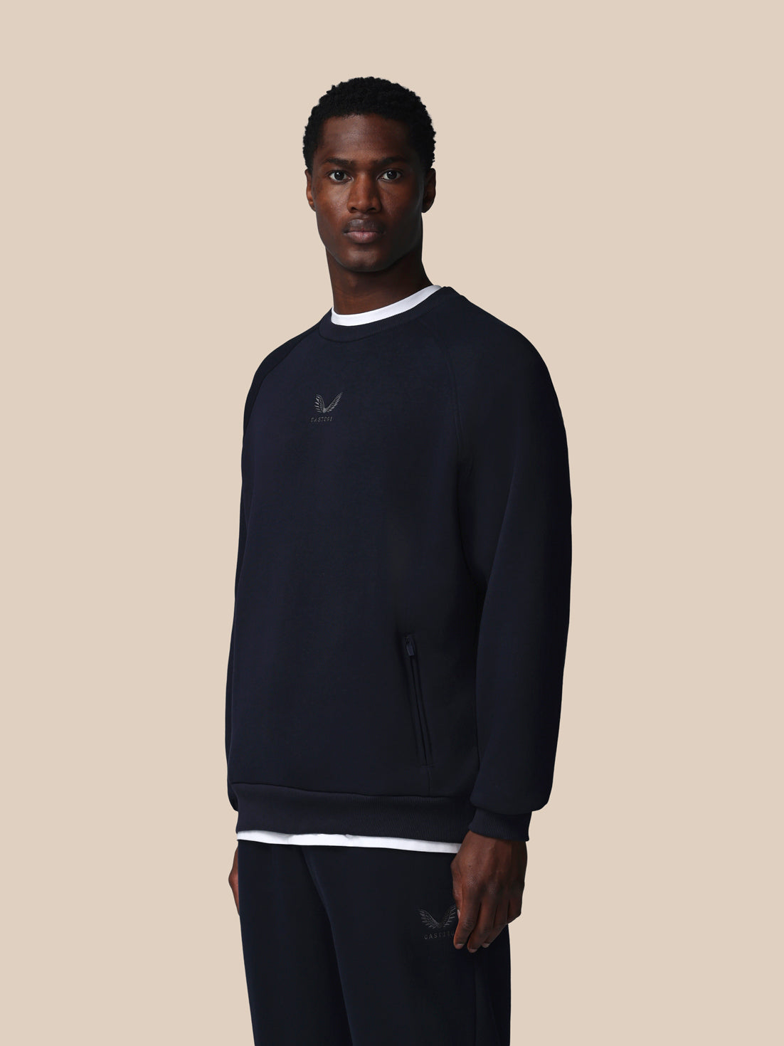 Man wearing a dark blue sweatshirt with a logo on a beige background