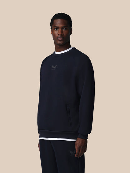 Man wearing a dark blue sweatshirt with a logo on a beige background