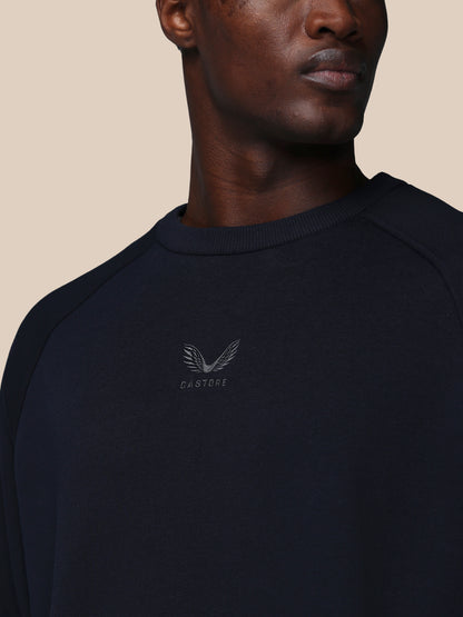 Man wearing a black sweatshirt with a logo on a beige background