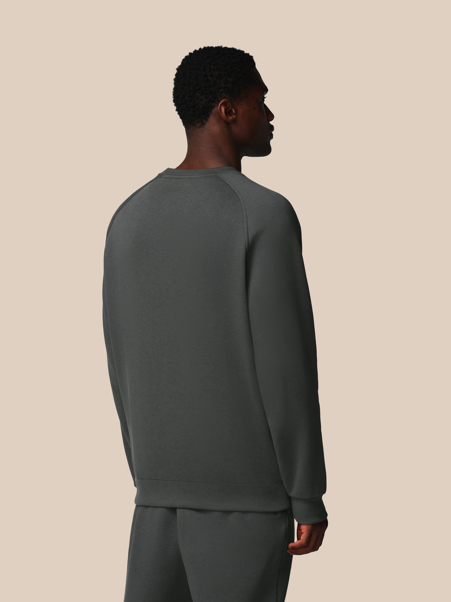 Person wearing a gray sweatshirt and pants on a beige background