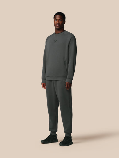 Man wearing a gray sweatshirt and pants on a beige background