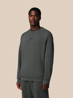 Man wearing a gray sweatshirt with a logo on a beige background