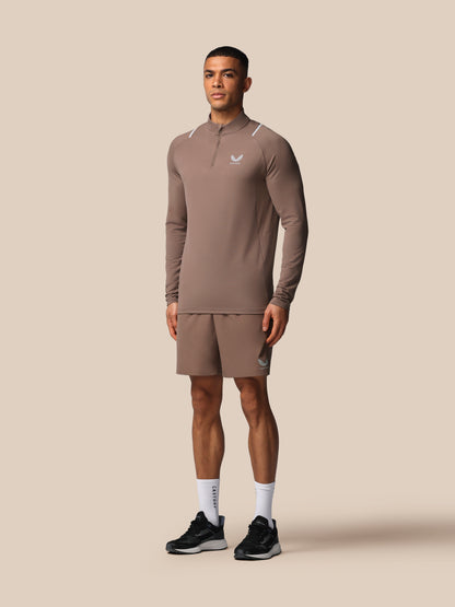 Man wearing a brown athletic outfit with a logo on a beige background