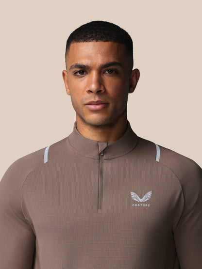 Man wearing a brown athletic jacket with a logo on a beige background