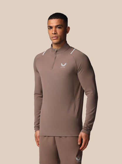 Man wearing a brown athletic outfit with a logo on a beige background