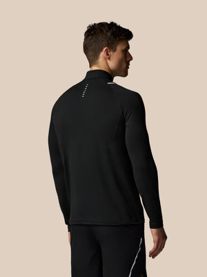 Man wearing a black athletic jacket and pants on a beige background