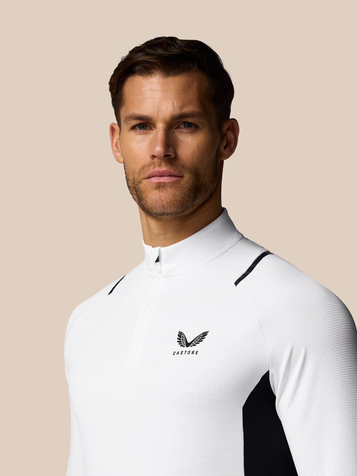Man wearing a white athletic outfit with a logo on a beige background