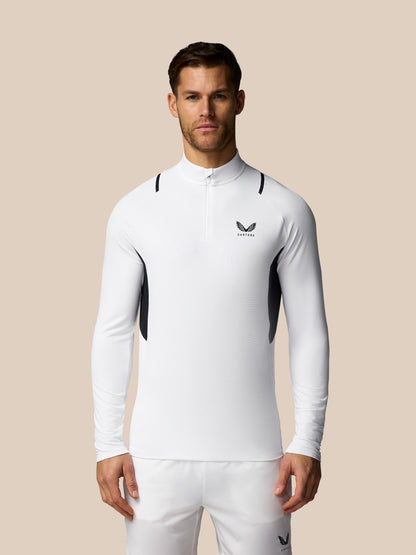 Man wearing a white athletic outfit with a logo on a beige background