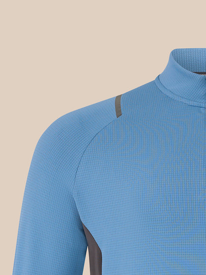 Close-up of a light blue textured athletic top with a mock neck and dark gray shoulder detail, shown against a solid beige background.
