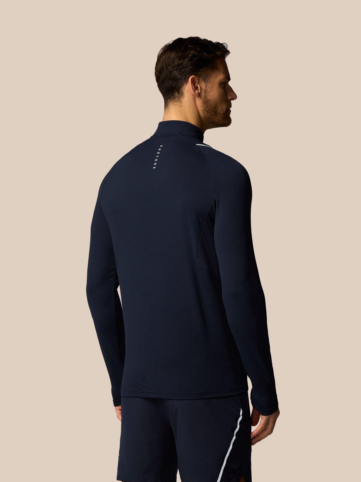 Man wearing a navy blue athletic outfit on a beige background