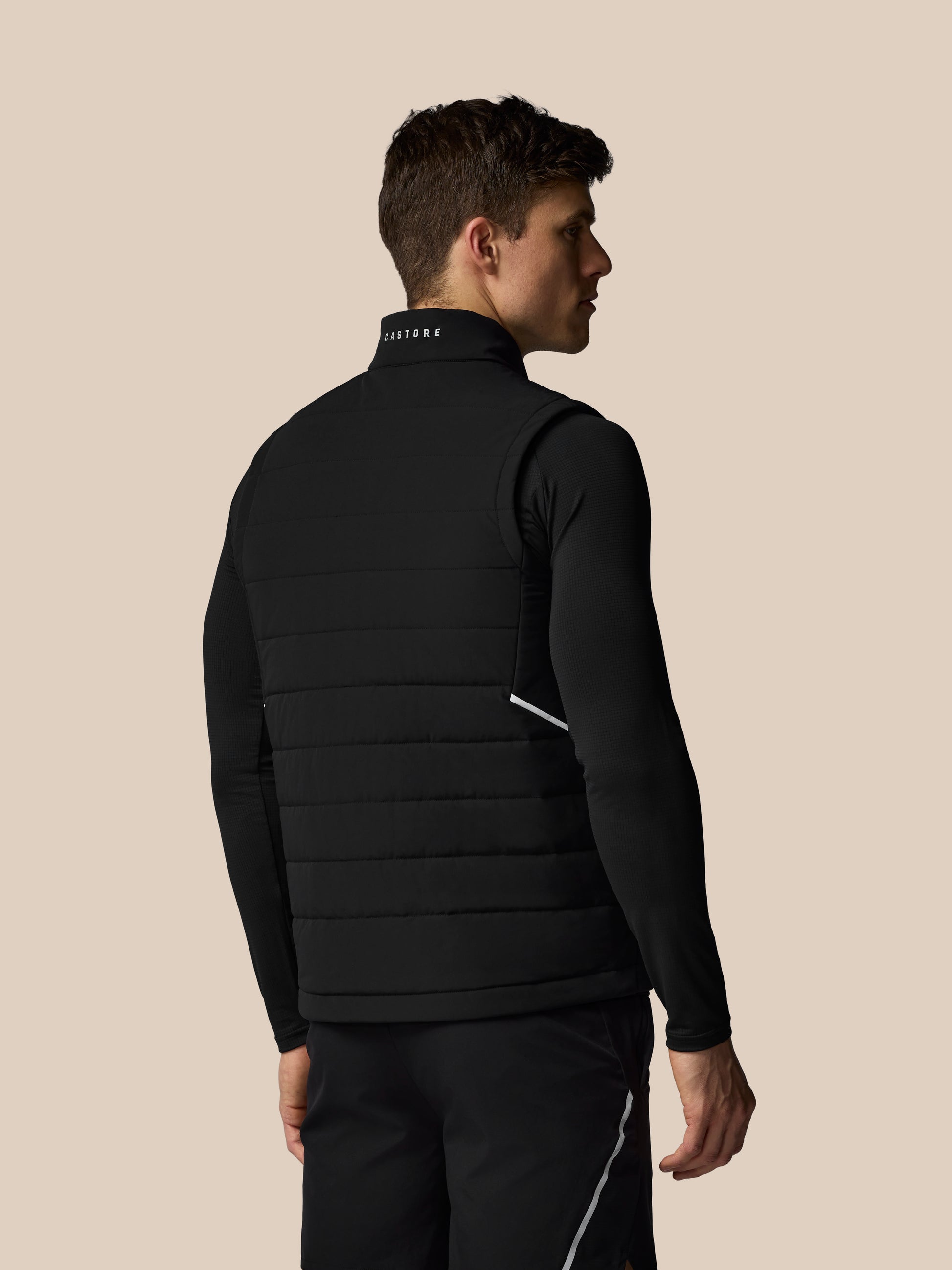 Man wearing a black puffer vest on a beige background