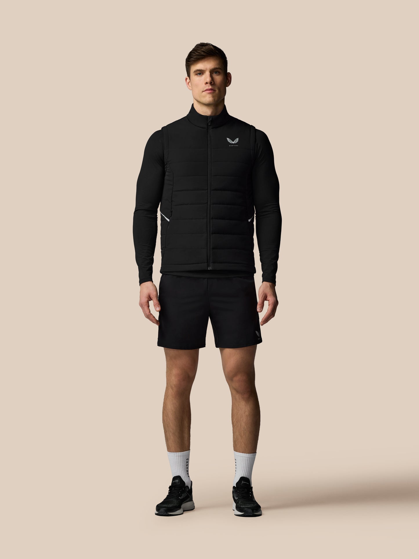 Man wearing a black jacket and shorts on a beige background