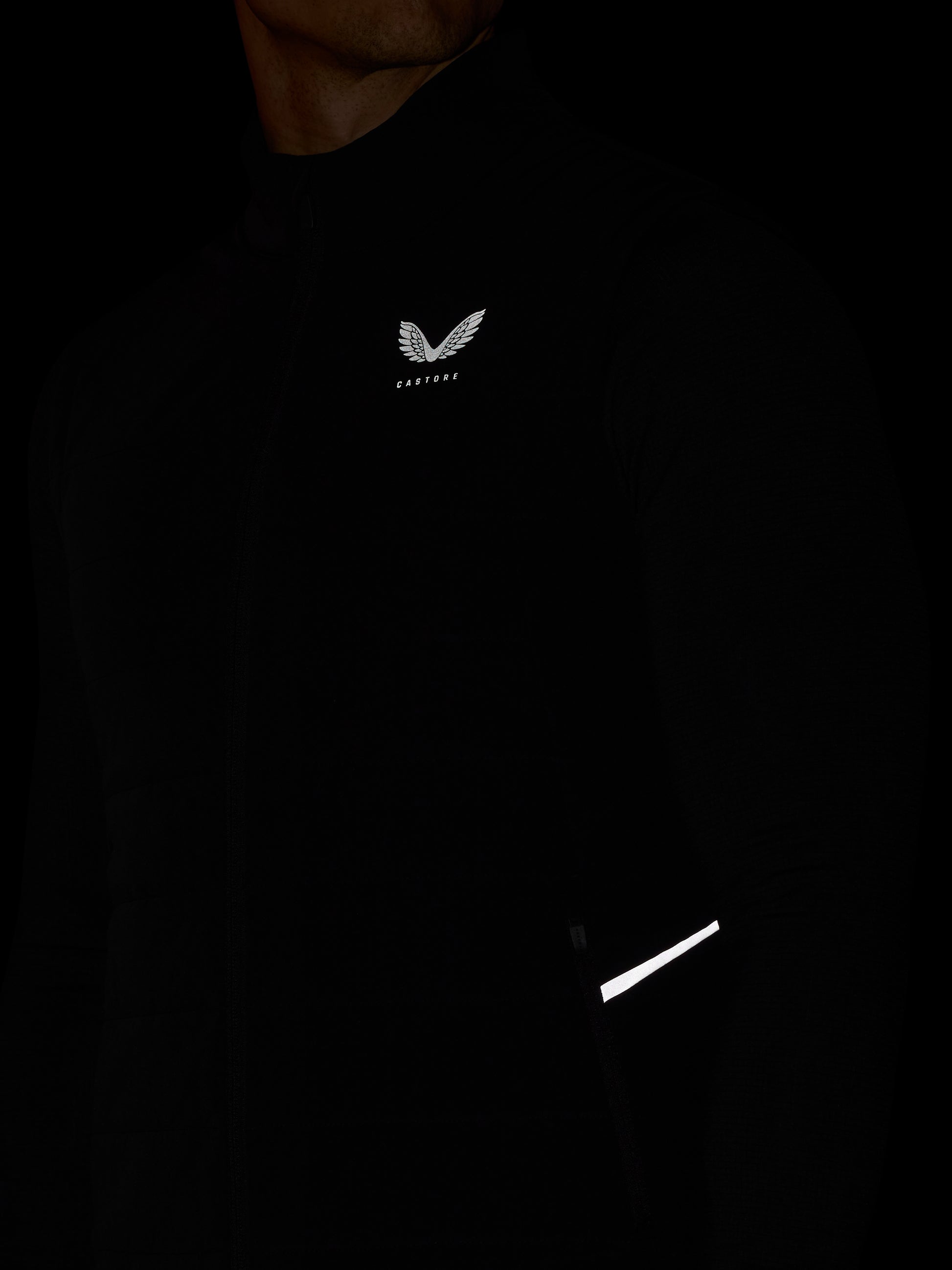 Black hoodie with a logo on the chest and reflective strip on the sleeve against a dark background