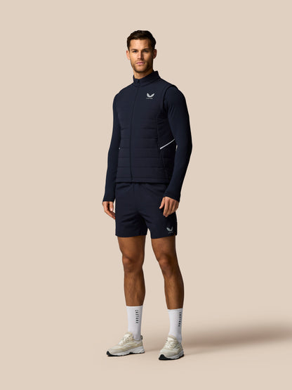Man wearing a navy athletic outfit with a logo on a beige background