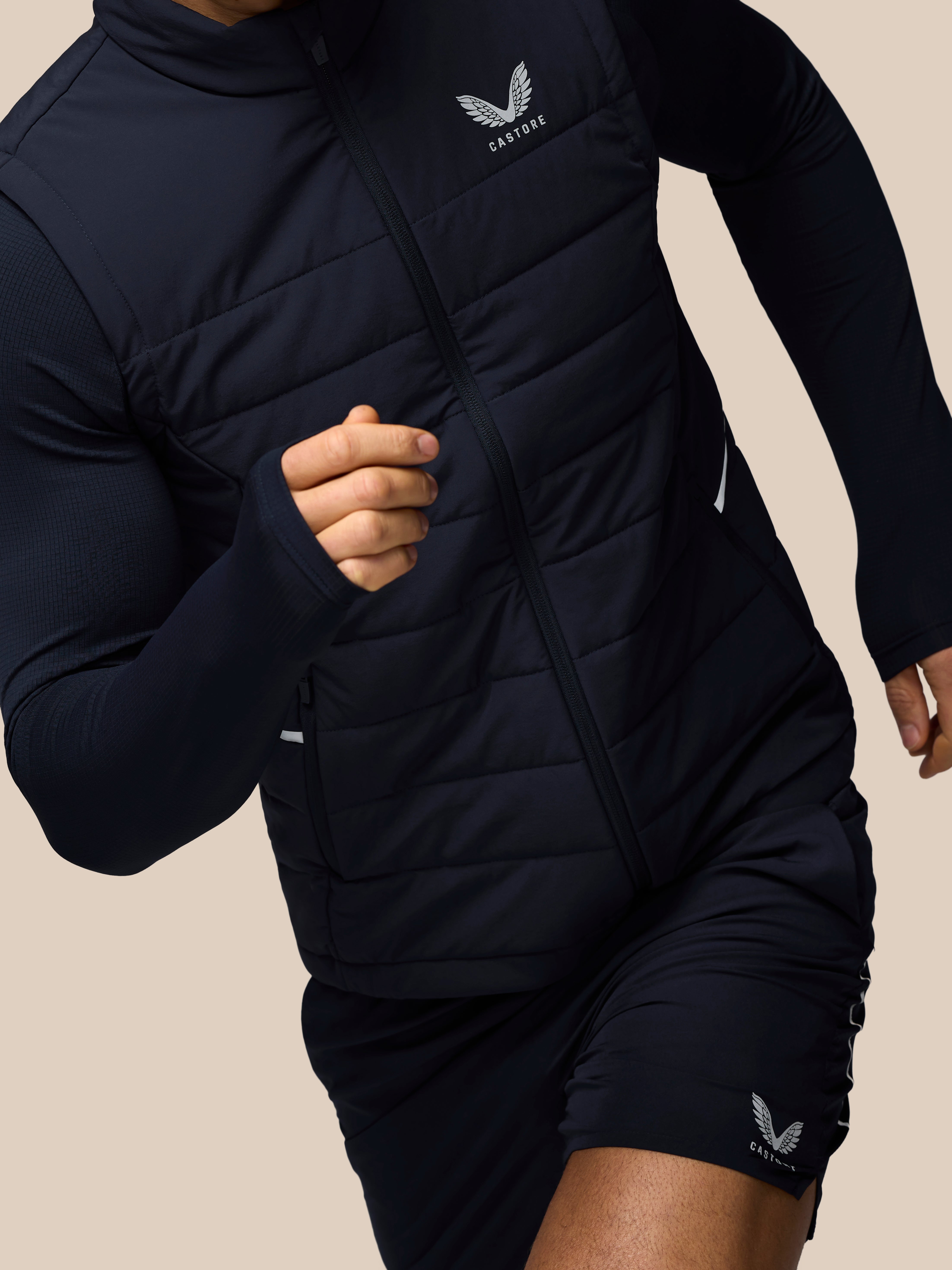 Person wearing a navy athletic outfit with a brand logo on a beige background
