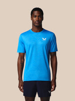 Man wearing a blue athletic shirt with a logo on a beige background