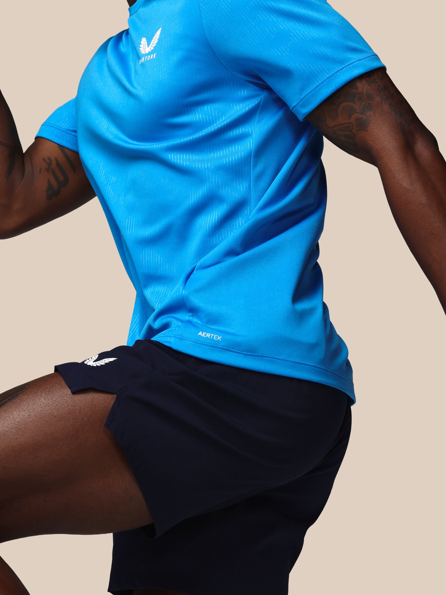 Person wearing a blue athletic shirt and black shorts on a beige background
