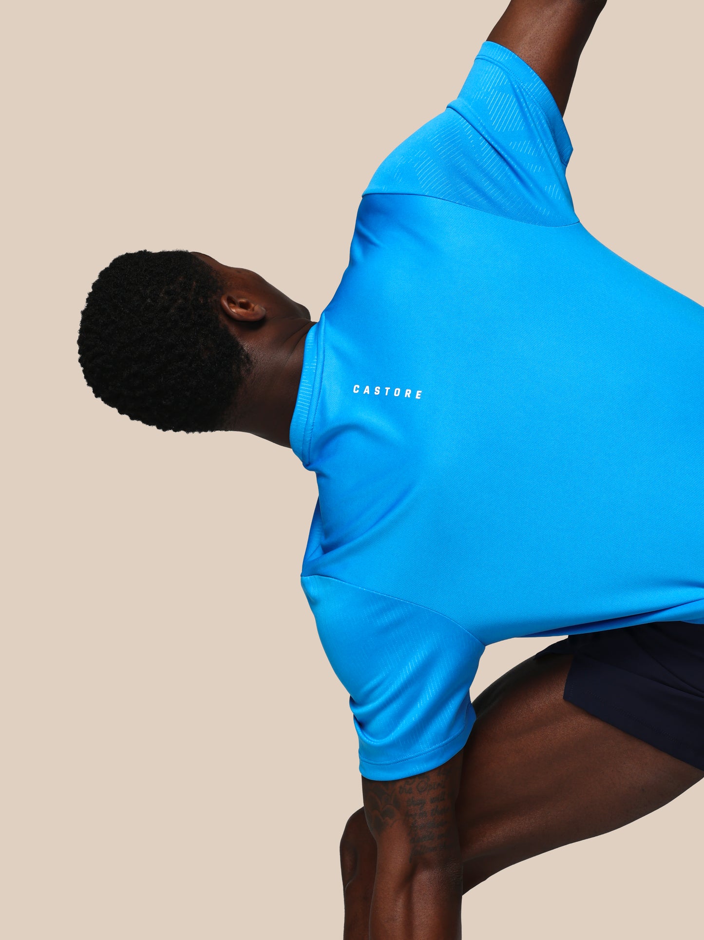 Person wearing a blue athletic outfit with 'Cayler & Sons' branding on a beige background