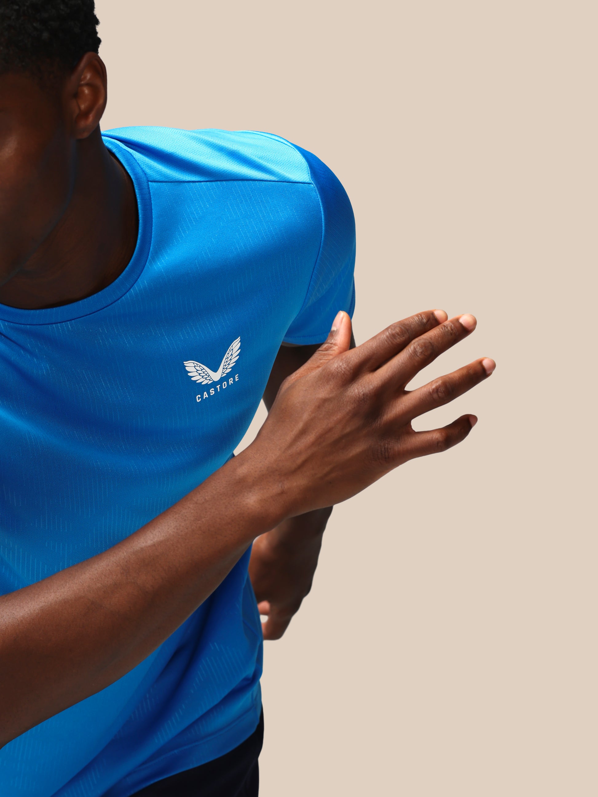 Person wearing a blue athletic shirt with a logo on a beige background