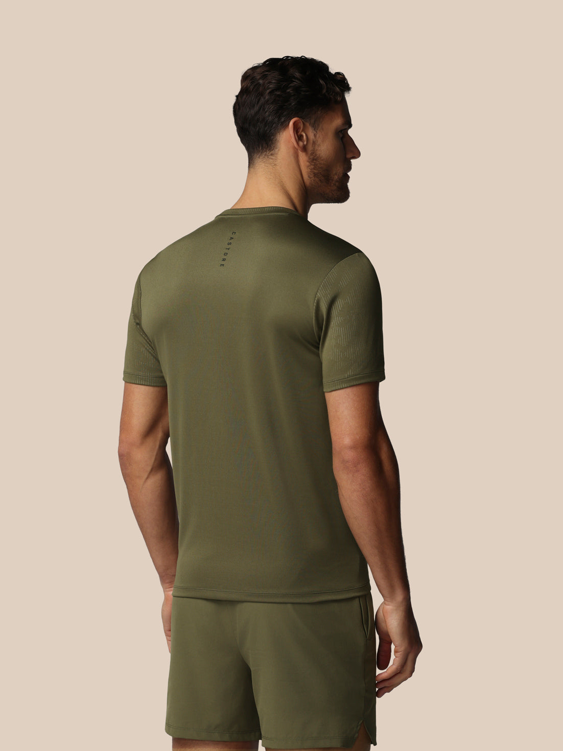 Man wearing an olive green athletic outfit on a beige background