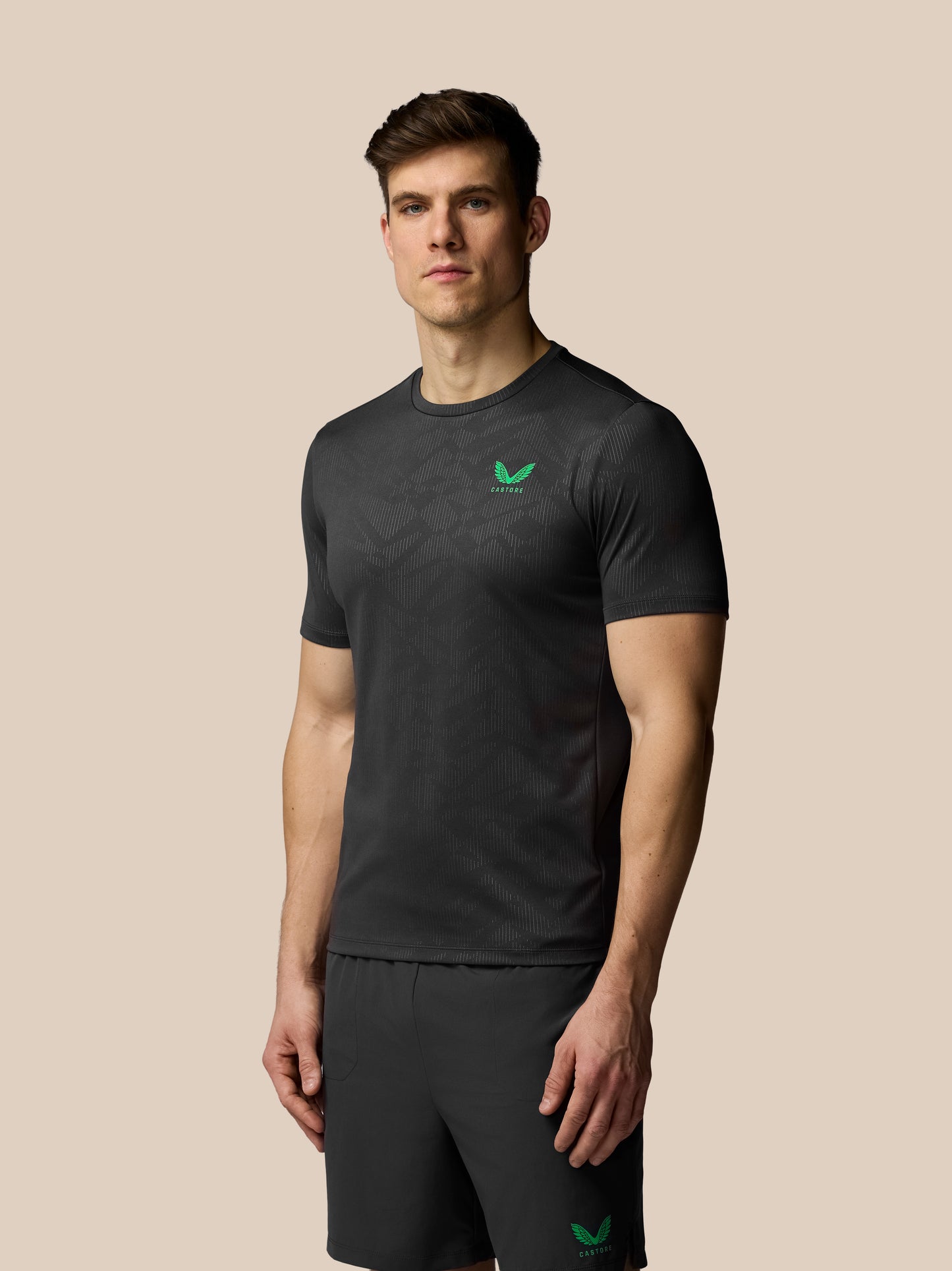 Man wearing a black t-shirt with a green logo on a beige background