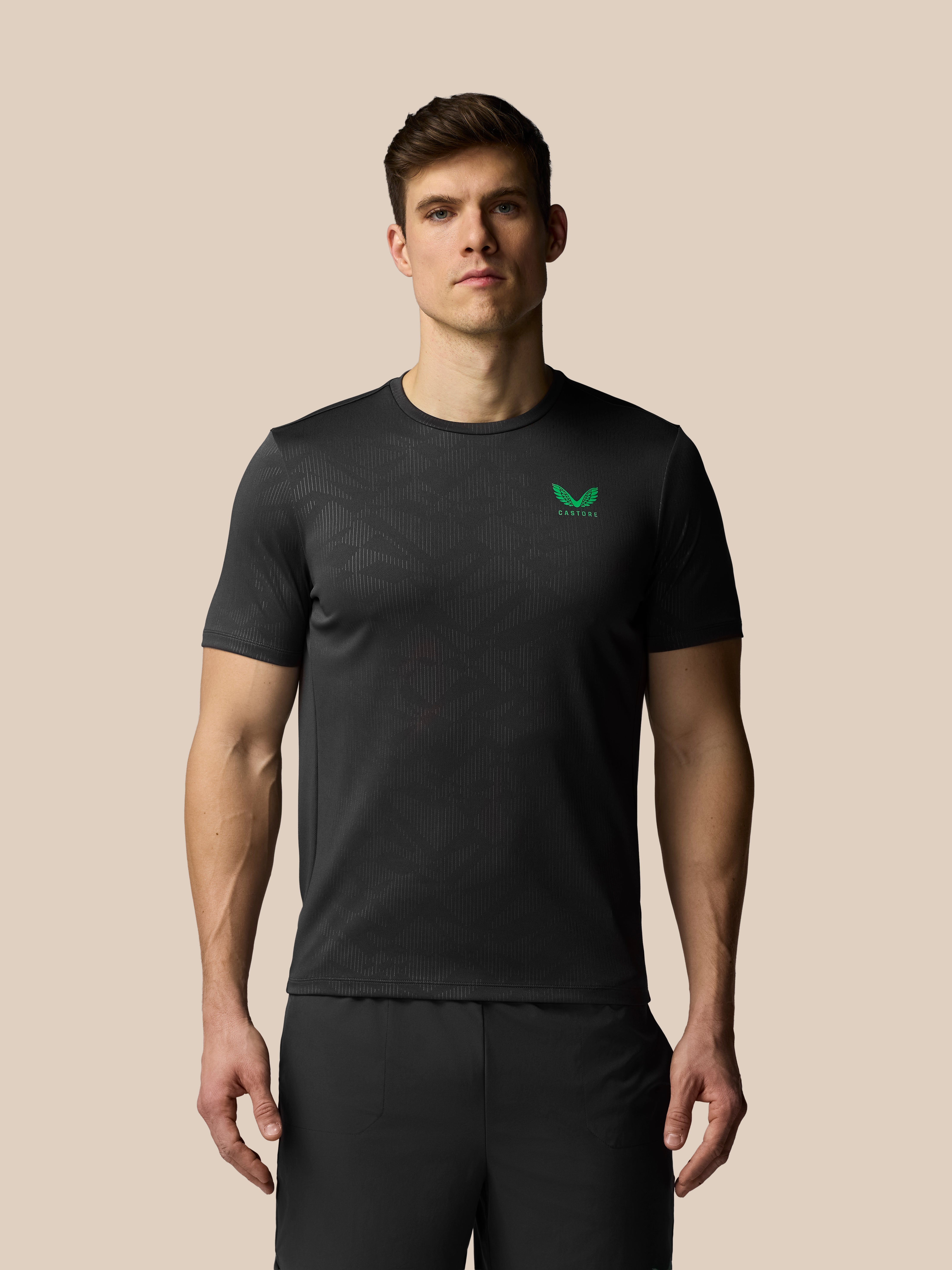 Man wearing a black t-shirt with a green logo on a beige background
