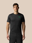 Man wearing a black t-shirt with a green logo on a beige background