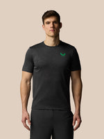Man wearing a black t-shirt with a green logo on a beige background