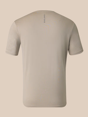 A light beige short-sleeve crewneck t-shirt shown from the back, featuring a small vertical 'CASTORE' logo printed in dark gray near the upper center back, set against a solid light beige background.