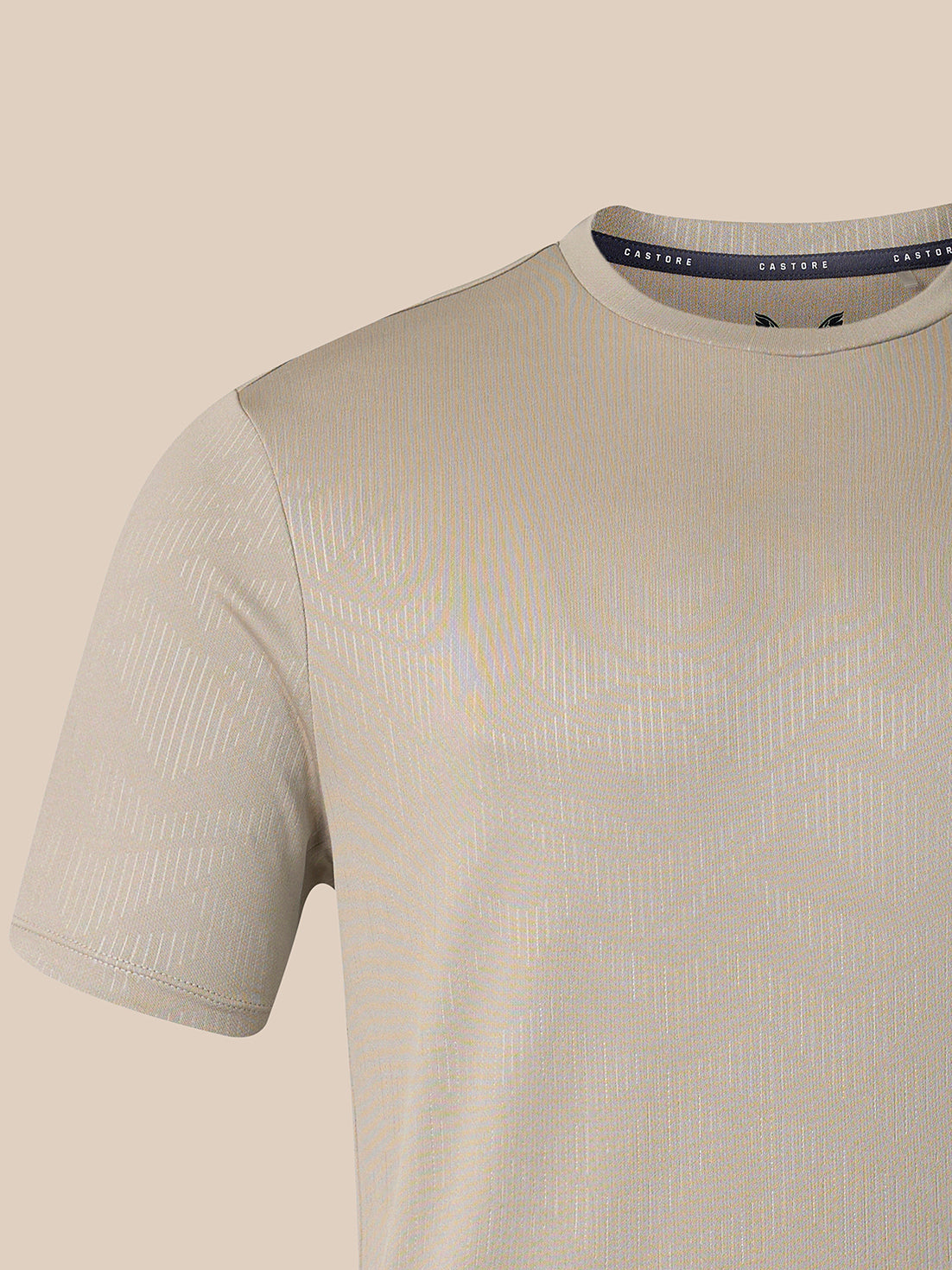 A close-up of a short-sleeve crew-neck t-shirt in a light beige or cream color, featuring a subtle vertical textured stripe pattern. The inner collar label shows the brand name 'CASTORE'.