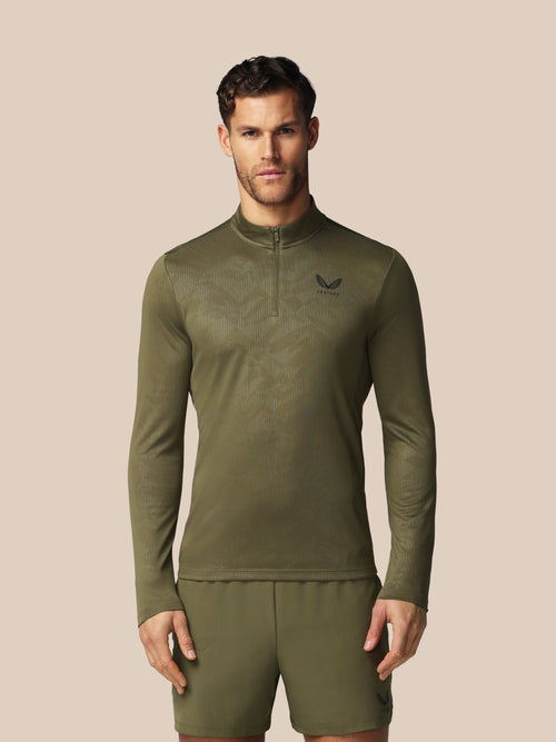 Man wearing a green athletic outfit with a logo on a beige background