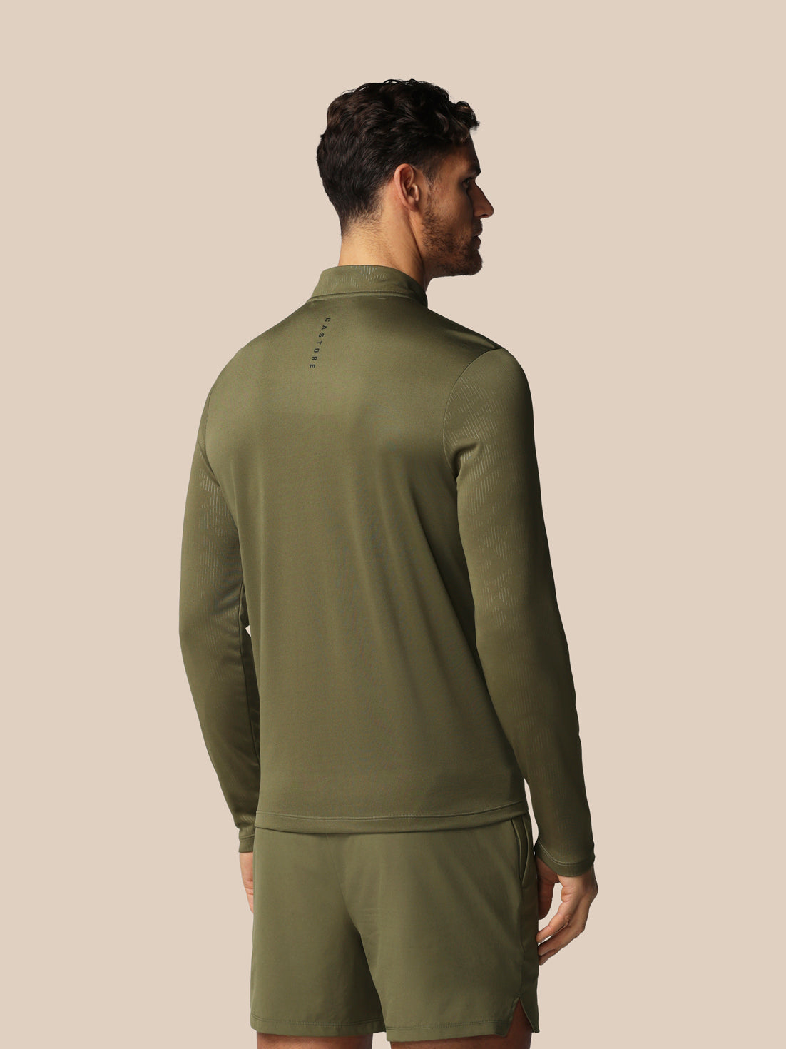 Man wearing an olive green tracksuit against a beige background