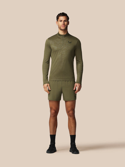 Man wearing a green athletic outfit with a brand logo on a beige background