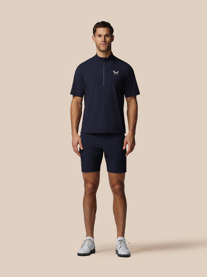 Man wearing a navy blue athletic outfit with a logo on a beige background