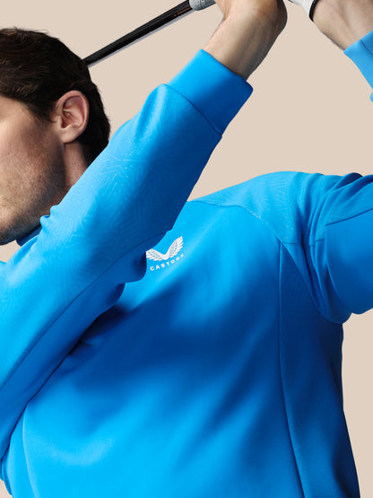 Person wearing a blue jacket with a logo on a beige background