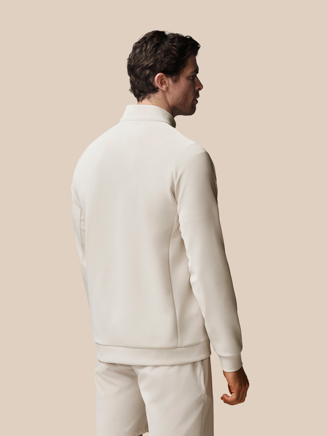 Man wearing a white tracksuit against a beige background