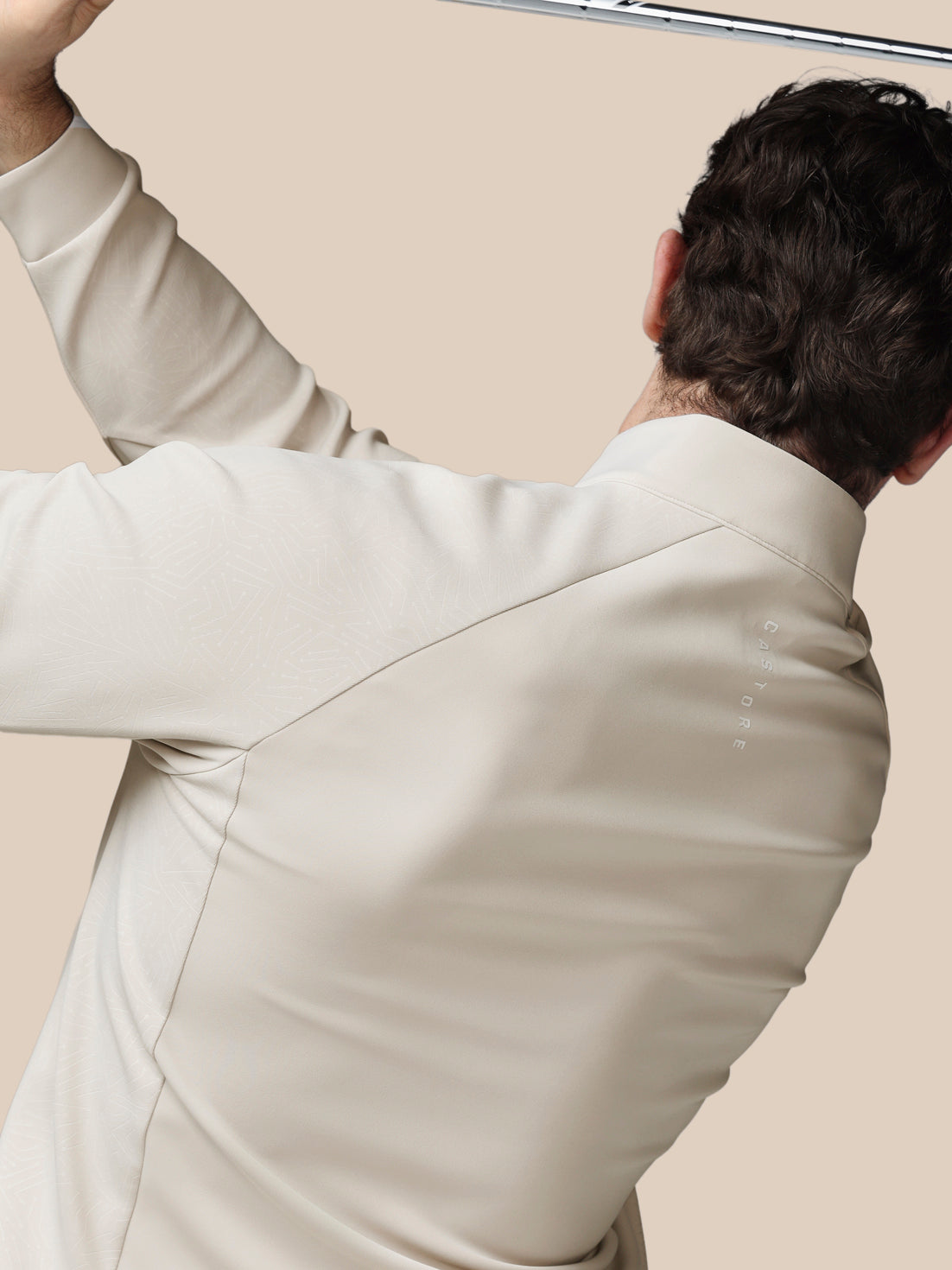 Person wearing a light-colored suit against a beige background