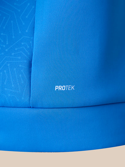 Close-up of a bright blue fabric product with the word PROTEK printed in white near the center, showing a textured surface and a lighter blue patterned section on the left.