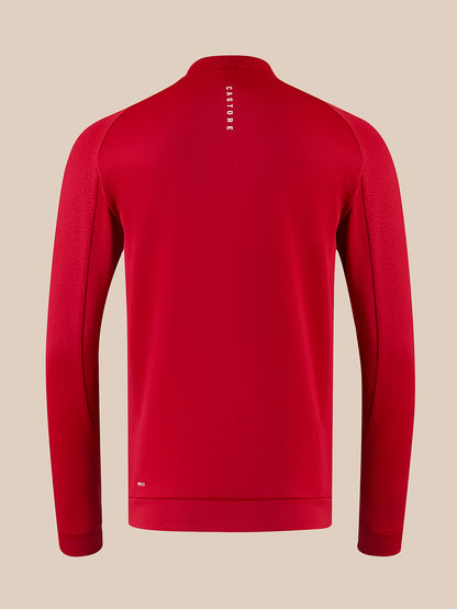 A red long-sleeve athletic quarter-zip pullover shown from the back, featuring a vertical white 'CASTORE' logo on the upper back, set against a solid beige background.