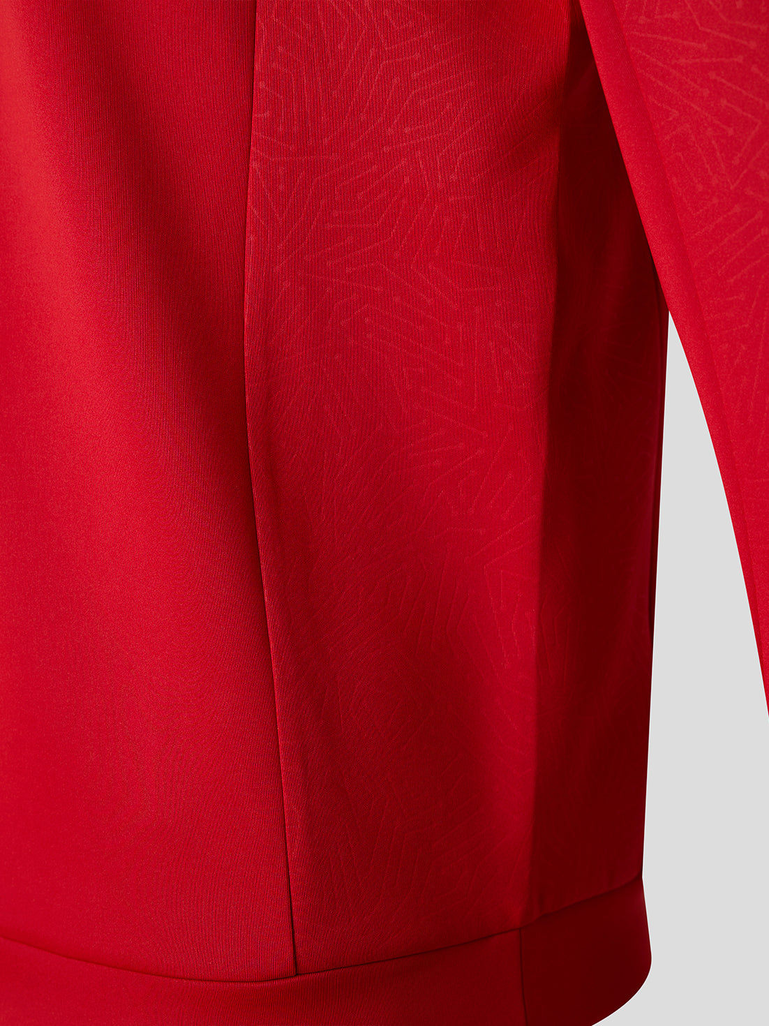 Close-up of a bright red quarter zip showing the fabric texture, vertical seam, and part of the sleeve against a light gray background.