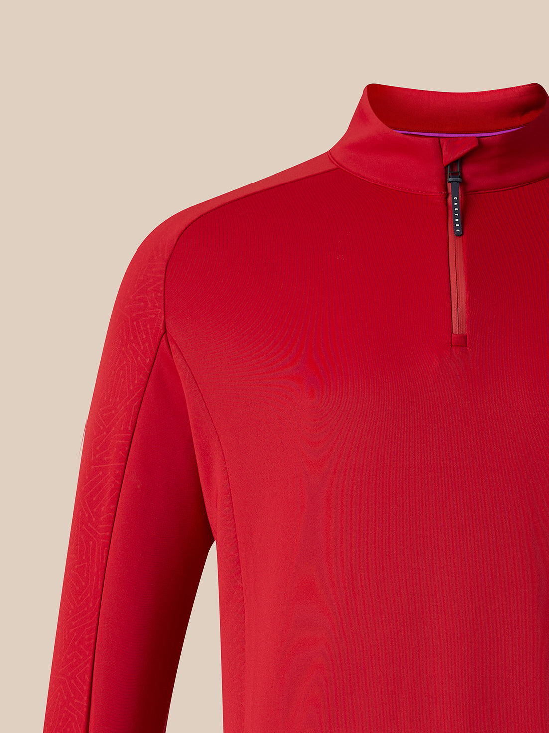 A close-up of a red long-sleeve athletic quarter-zip pullover, showing the collar, zipper, and textured fabric against a solid beige background.