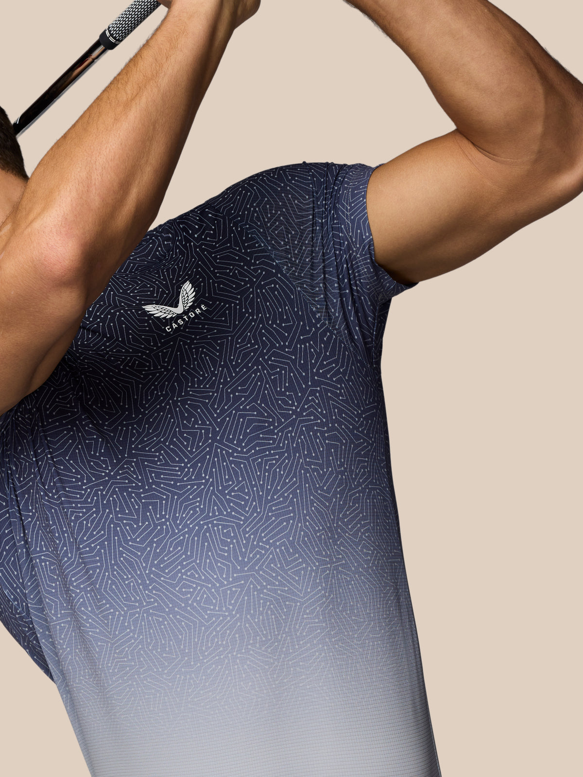 Person wearing a blue athletic shirt with a logo on a beige background
