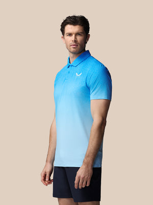 Man wearing a blue gradient polo shirt with a logo on a beige background