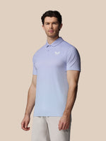 Man wearing a light blue polo shirt with a logo on a beige background