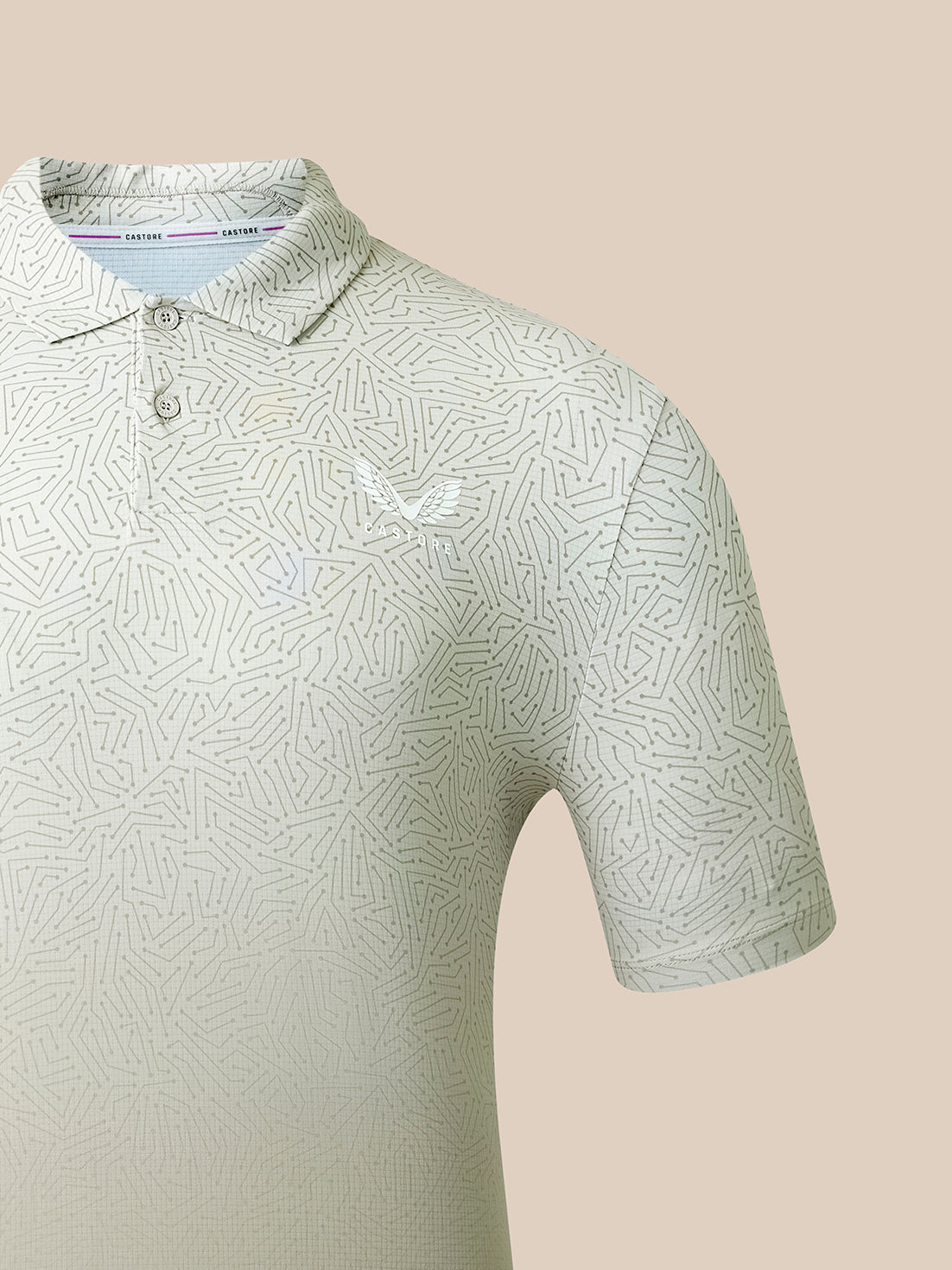 A close-up of a short-sleeve polo shirt with a light beige and white geometric pattern, featuring a small white embroidered eagle logo on the chest. The shirt is shown on a solid beige background.