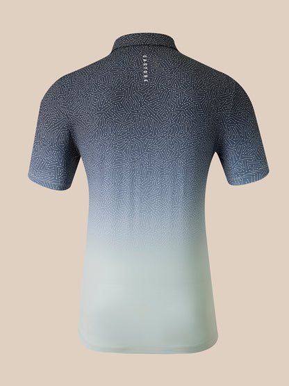 A short-sleeve polo shirt shown from the back, featuring a dark gray and blue geometric pattern that fades into a light mint green at the hem, set against a solid beige background.