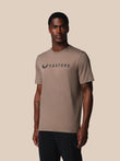 Man wearing a brown t-shirt with 'Castore' logo on a beige background