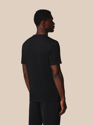 Man wearing a black t-shirt and pants against a beige background